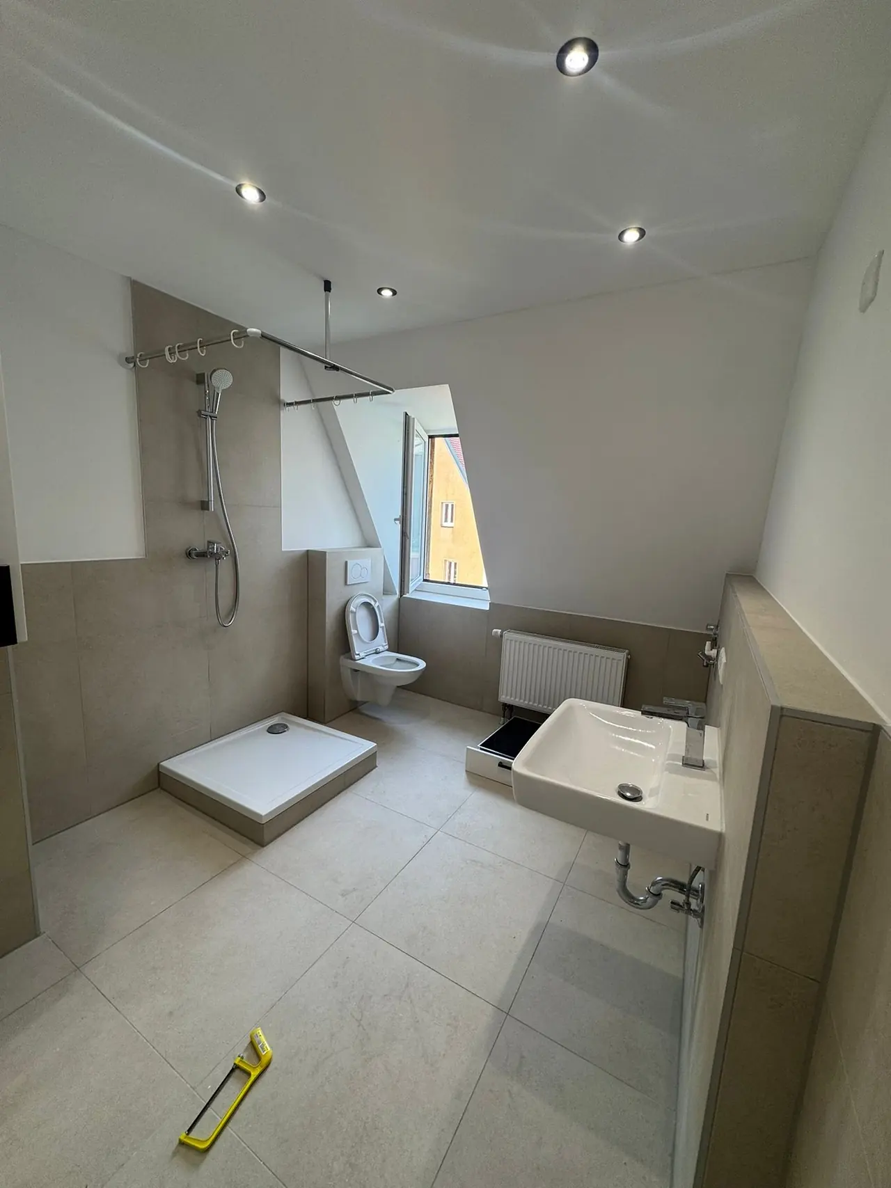 Nürnberg, Badezimmer nach der Sanierung: Dusche mit Glaswand, WC, Waschtisch und hellgraue Fliesen