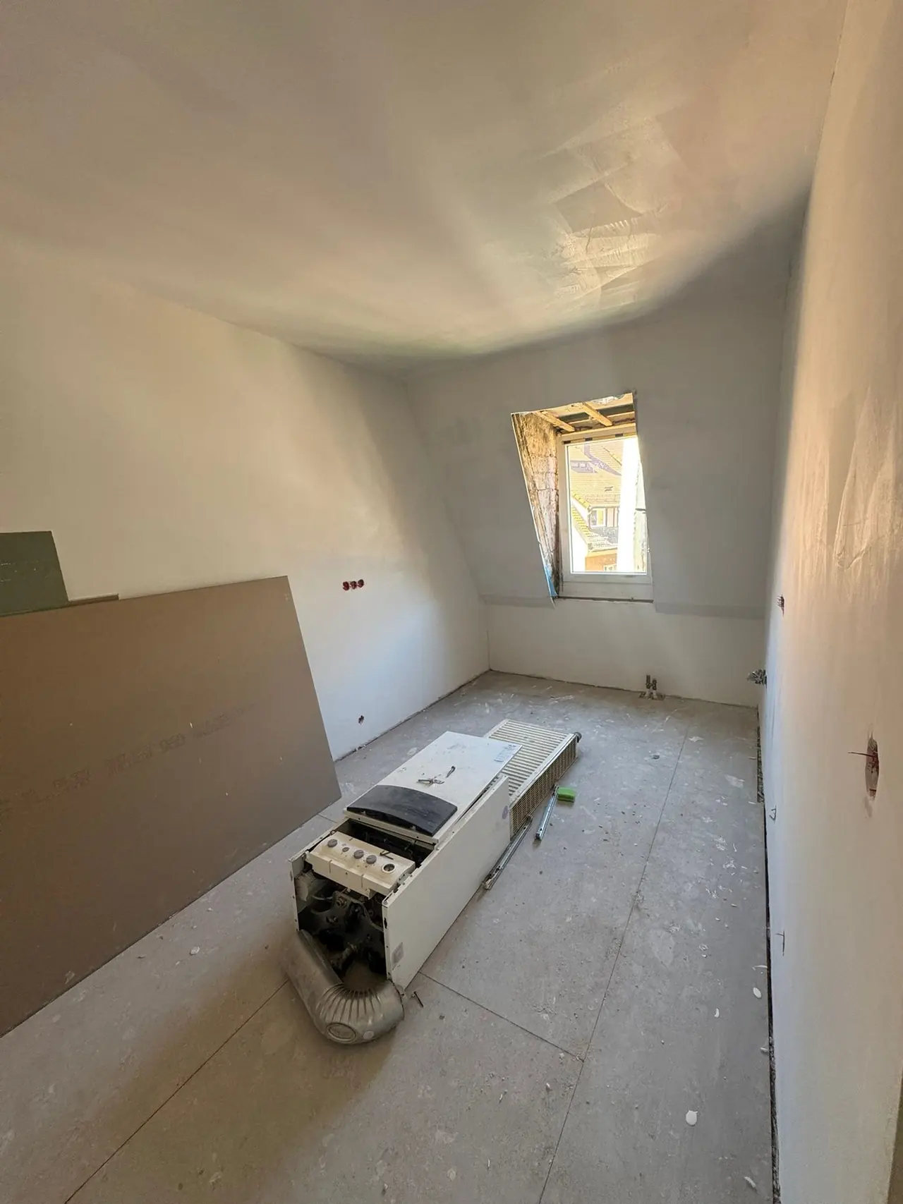 Nürnberg, Zimmer vor der Sanierung: Rohboden unter der Dachschräge mit abgestellten Bauteilen