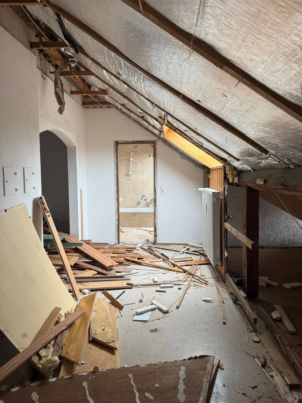 Rückbau im Dachgeschoss: herausgerissene Verkleidungen und Bauschutt unter der Dachschräge