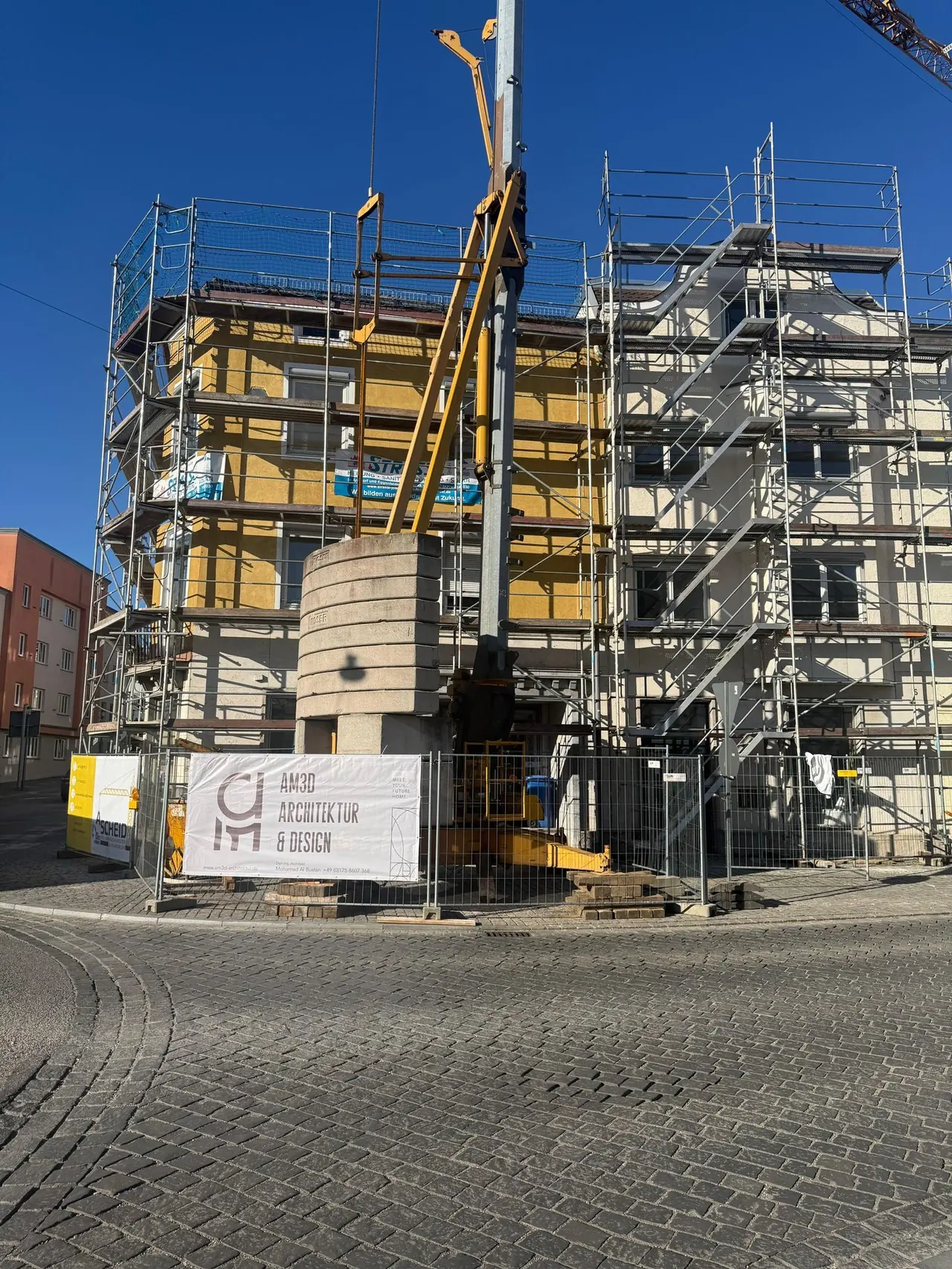 Eingerüstete Altbaufassade während der Sanierung im Bestand, davor Baukran und Baustellenschild