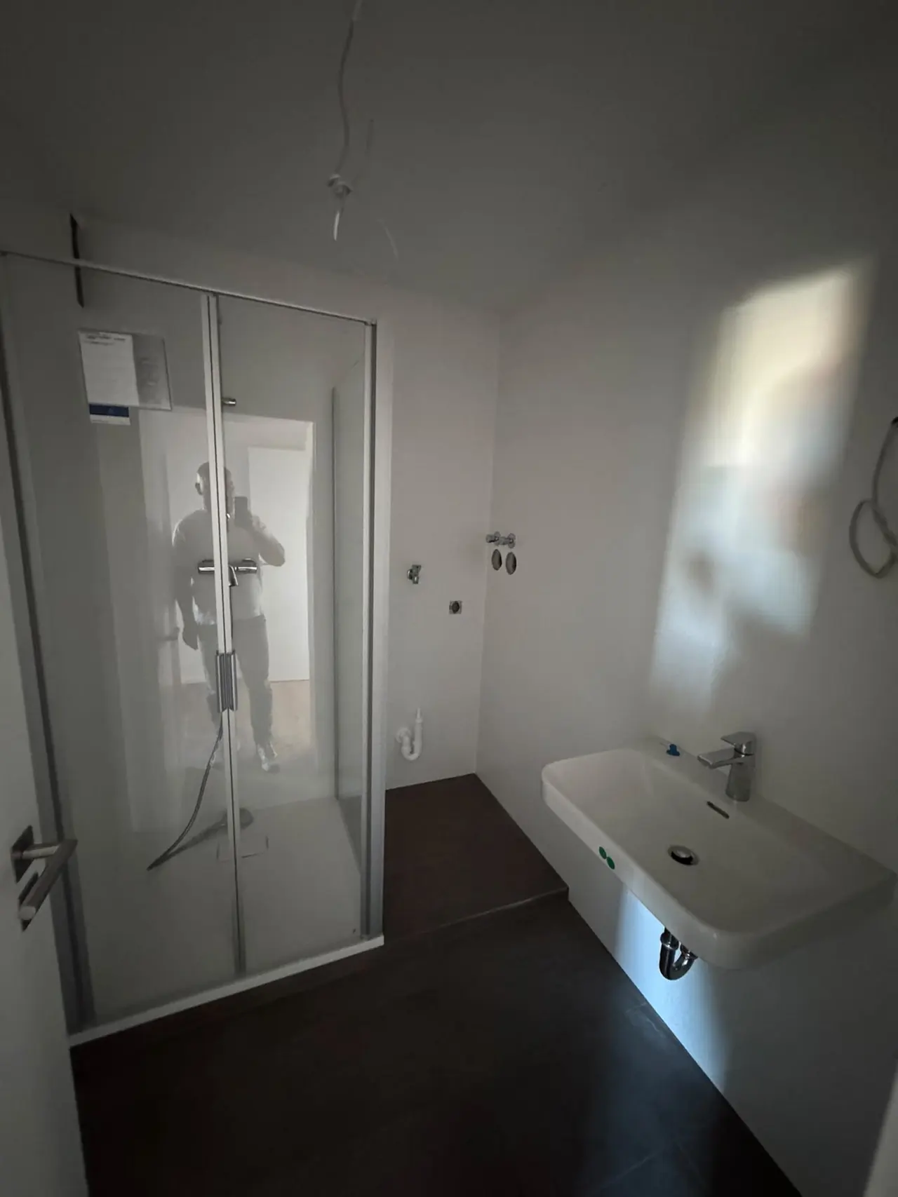 Straubing, Badezimmer nach der Sanierung: Dusche mit Glastüren, Waschtisch und dunkler Bodenbelag
