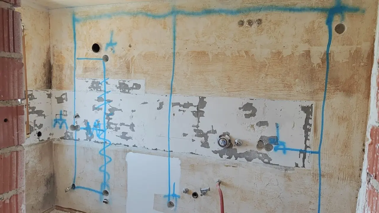 Straubing, Küchenwand vor der Sanierung: rohe Wand mit blau markierten Anschlüssen, noch ohne Einbauten